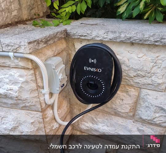 עמדת טעינה לרכב חשמלי ליד קיר אבן